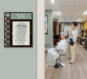 A senior woman gets her hair styled in an assisted living beauty salon, marked with a 2-line Diverge&trade; informational sign with insert window.