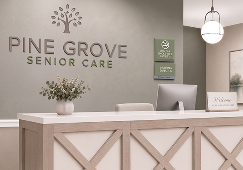 A senior living center front desk with the name in dimensional letters and a Facets no smoking policy sign and nursing director nameplate.