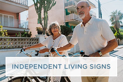 An older couple enjoys a conversation while walking their bikes through the grounds of an independent living facility.