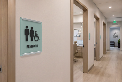 Resident room sign with photo insert beside an older woman seated in her memory care living room