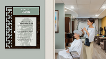 A senior woman gets her hair styled in an assisted living beauty salon, marked with a 2-line Diverge&trade; informational sign with insert window.