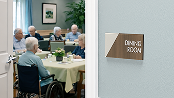 An Incline room sign labels a nursing home dining room where residents are gathered to socialize over a meal.