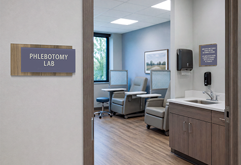 A phlebotomy lab with specimen collection bays and staff-use sink with a bilingual handwashing reminder.