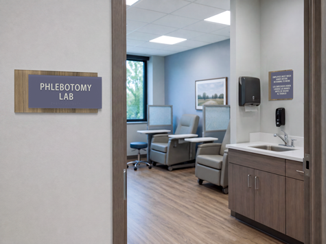 A phlebotomy lab with specimen collection bays and staff-use sink with a bilingual handwashing reminder.