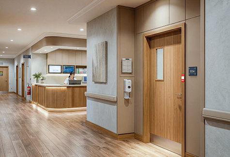 A resident walks through a modern senior care corridor with clear room identification and accessible wayfinding signs.